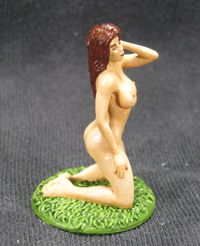 Erotic figurine  of a nude half-elf female, kneeling on the grass.
